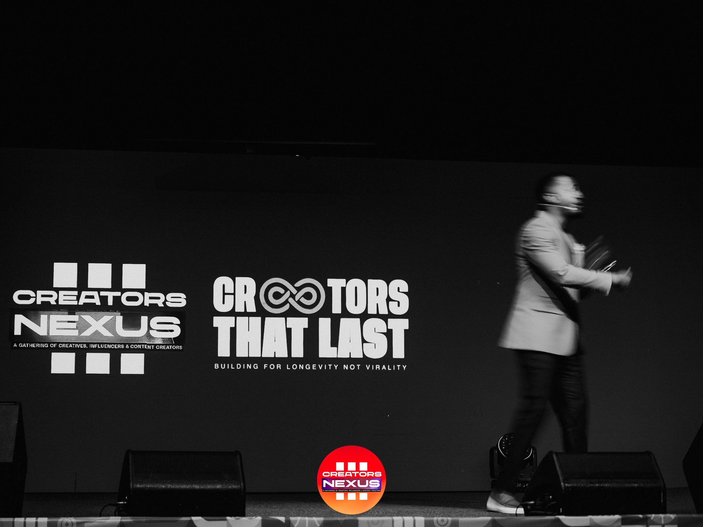 A speaker mid-address on the Creators Nexus III main stage, with the Creators Nexus and "Creators That Last" logos projected behind him.